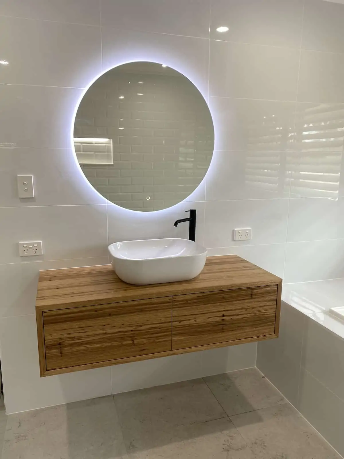 sink on floating basin with round backlit mirror as part of luxury bathroom renovations